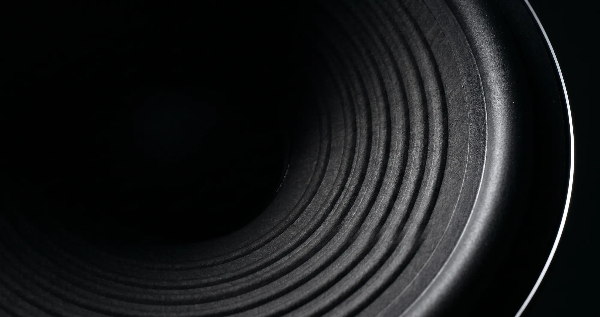 Loop Audio Works, precision audio installation in South India. Macro of concentric speaker cone rings lit by a narrow strip light.