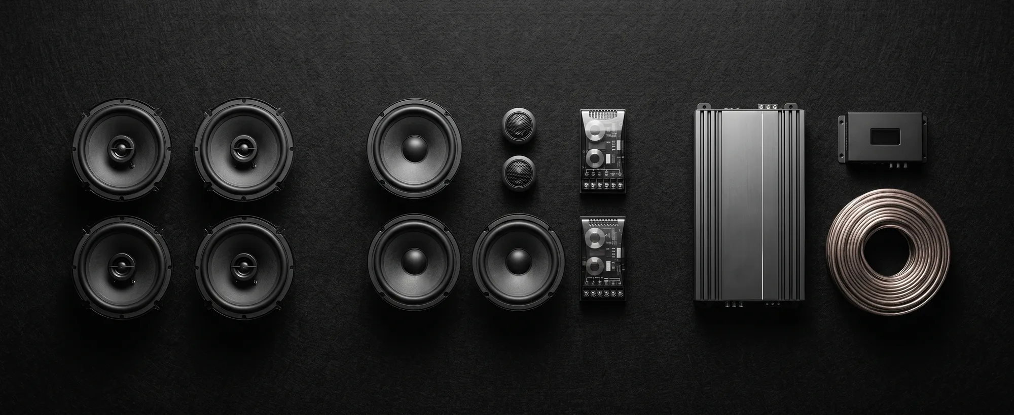 Car audio system components laid out by price tier, South India. Overhead flat-lay of a full car audio system arranged by tier.