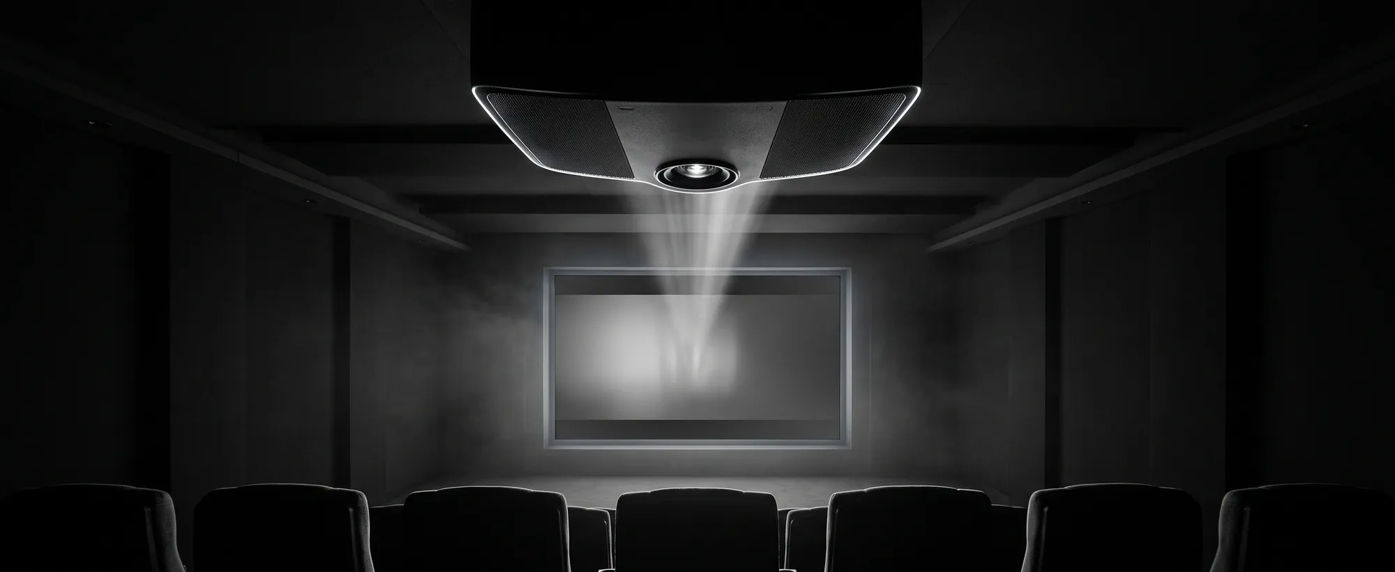 4K laser projector and 135-inch screen in a private home cinema. A projector beam cutting through haze toward a large cinema screen.
